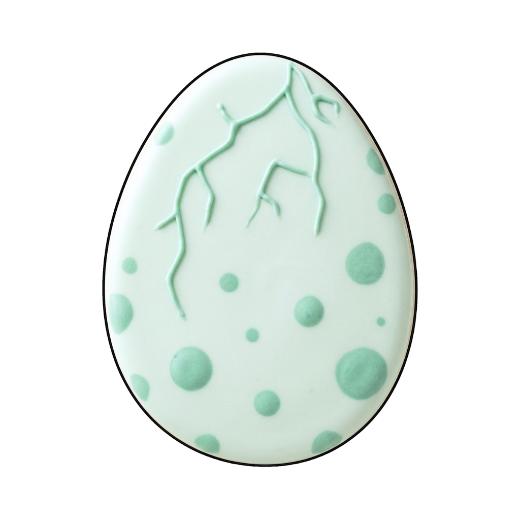 Mint dinosaur egg cookie with darker mint spots and cracked shell lines near the top